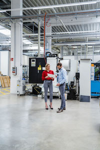 Businesswoman holding tablet pc discussing with colleague at factory