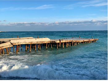 Wooden posts on beach against sky