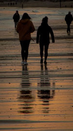 Rear view of silhouette people walking on beach