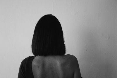 Rear view of woman standing against wall