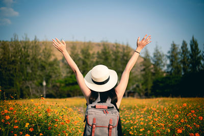 Woman standing by flowering plants on field