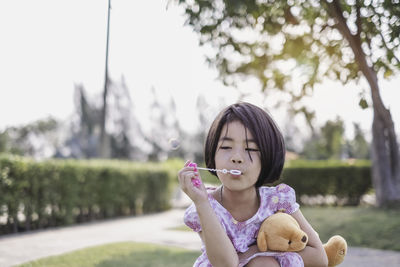 Portrait of a girl holding toy against trees