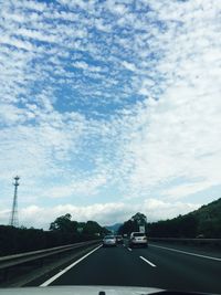 Cars on road against cloudy sky