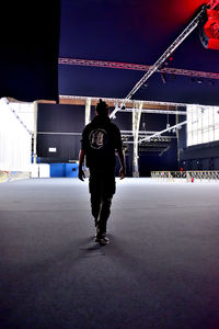 Full length rear view of man walking on illuminated bridge