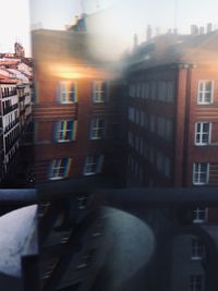 City street by buildings against sky during sunset