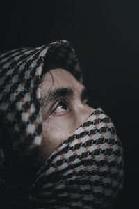 Close-up portrait of man wearing hat against black background