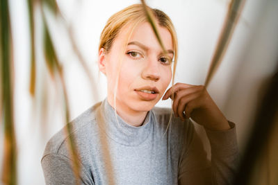 Portrait of a beautiful young woman holding curtain at home