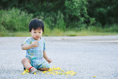 Full length of cute boy sitting on road