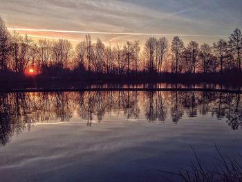 Reflection of trees in lake at sunset