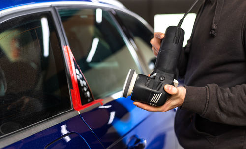 Midsection of mechanic polishing car at garage