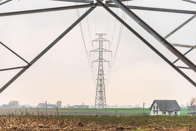 Electricity pylon on field against sky