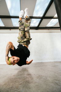 Full body of energetic young man doing acrobatic handstand while performing break dance