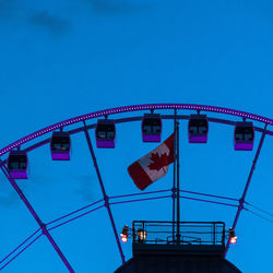 Low angle view of illuminated ferris wheel against blue sky