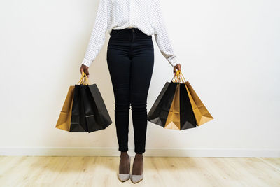 Young woman carrying paper shopping bags while standing against white background