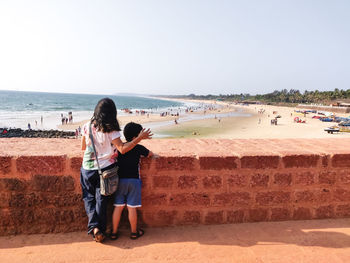 Rear view of family on beach against sky