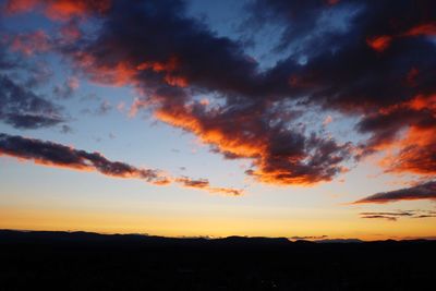 Silhouette landscape against dramatic sky during sunset