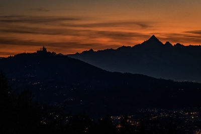 Scenic view of silhouette mountains against orange sky