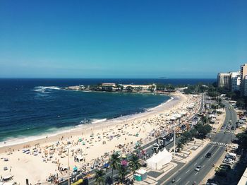High angle view of city by sea against clear blue sky