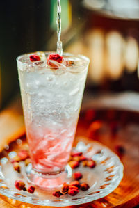 Iced rose syrup with soda topped with rose petals on wood table, summer refreshment drinks