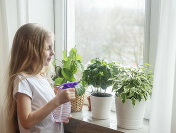 Girl spraying water on plants at home