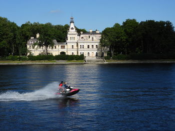 People in boat on river against trees