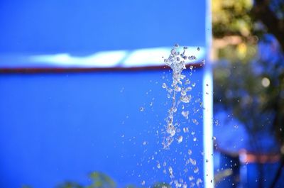 Close-up of water drop against blue sky