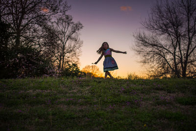 Little girl dancing sunset grass flowers silohette hill trees twirling