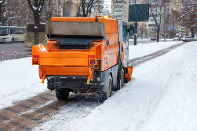 The sweeper cleans the snow on the cobbled sidewalk of the city street.