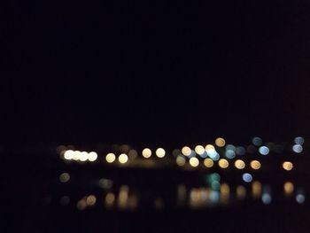 Defocused image of illuminated city against sky at night