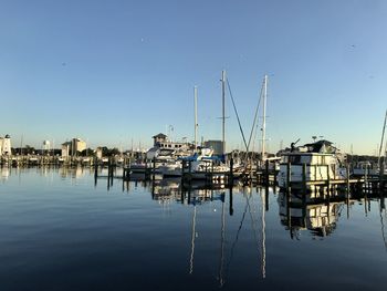 Sailboats in marina at harbor against clear sky