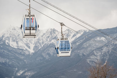 Ski lift over snowcapped mountains against sky