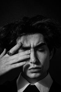 Close-up of man touching eyes against black background