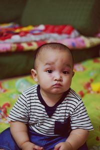 Portrait of cute baby boy sitting on bed