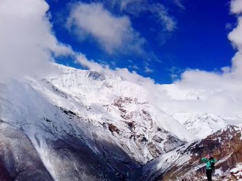 Man standing on snowcapped mountain against sky