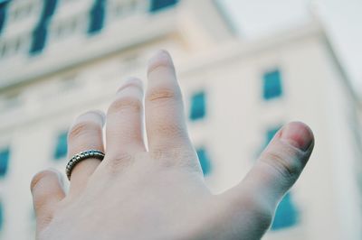 Cropped hand reaching towards building