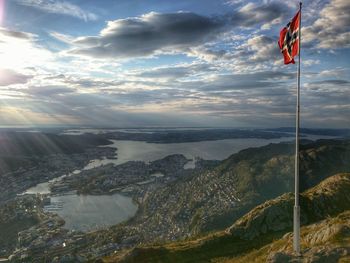Norwegian flag on mountain against cloudy sky