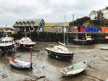 Boats moored at harbor against sky