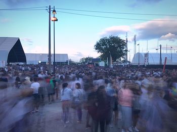 Crowd on road in city against sky