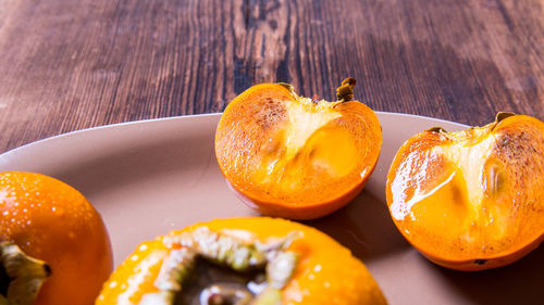 Persimmon cut into halves on a plate on a wooden table,copy space,closeup