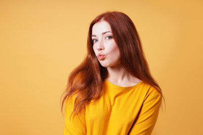 Portrait of young woman against yellow background