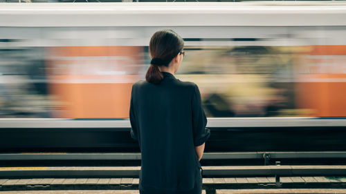 Rear view of woman standing at railroad station