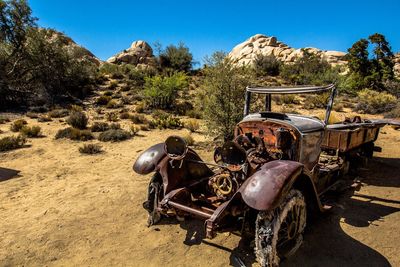 Abandoned truck on field against clear blue sky