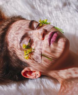 High angle view of woman with flowers on face sleeping at home