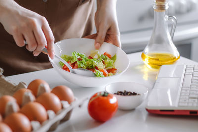 Woman preparing diet salad using digital cookbook. fresh vegetables and laptop in home kitchen. 