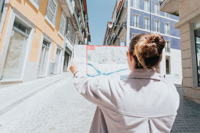 Rear view of woman standing against buildings