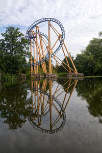 Ferris wheel by lake against sky