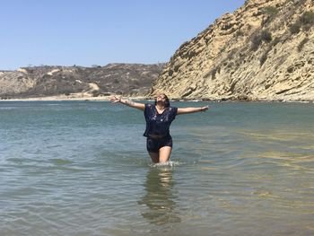 Woman standing in sea against sky