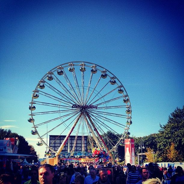 amusement park, large group of people, leisure activity, arts culture and entertainment, amusement park ride, lifestyles, ferris wheel, enjoyment, men, fun, person, blue, sky, clear sky, low angle view, tourist, built structure, mixed age range, copy space