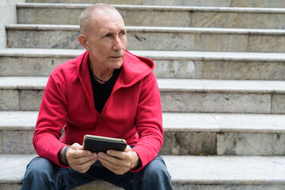 Man using mobile phone while sitting on staircase