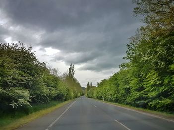 Empty road amidst trees against sky